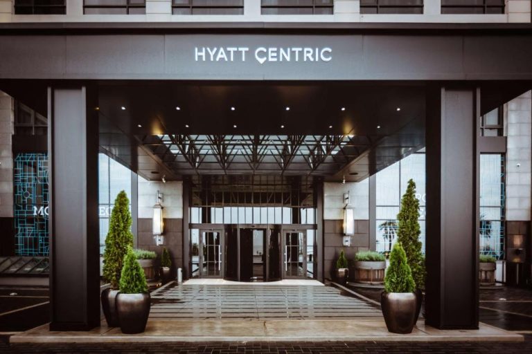 Entrada principal del Hyatt Centric Montevideo con marquesina iluminada y árboles decorativos