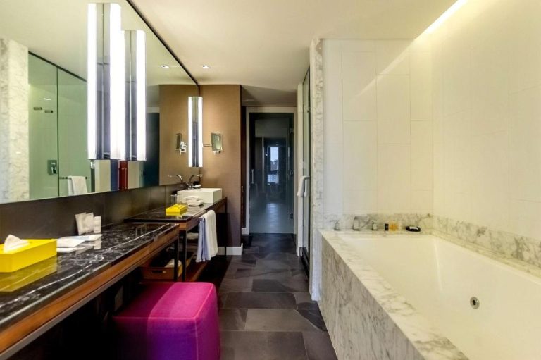 Baño de lujo con bañera de mármol blanco y tocador en el Hyatt Centric Montevideo