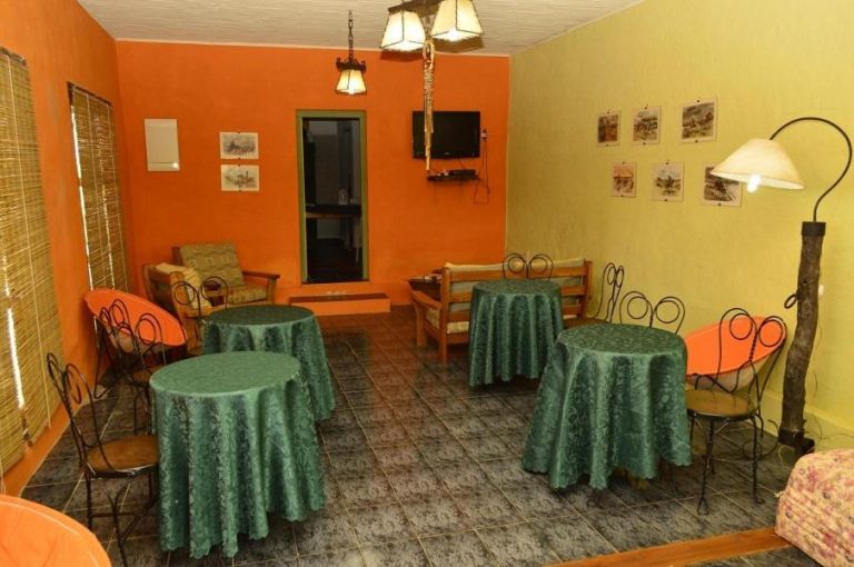 Salón comedor con mesas decoradas en verde de Alquimia Posada, ambiente acogedor con paredes naranjas