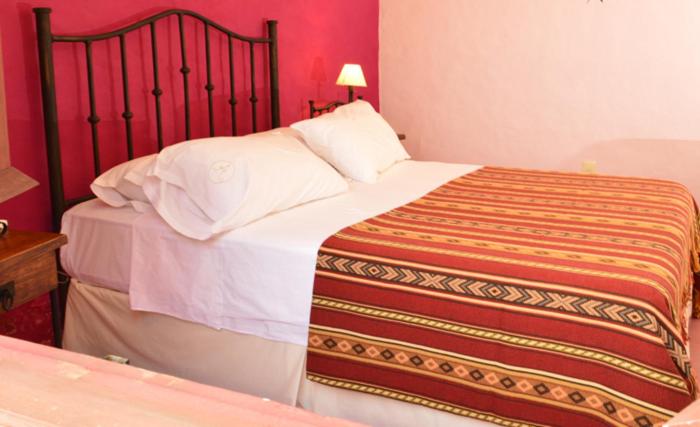 Habitación doble con cabecera de hierro forjado y colcha de diseño andino en Alquimia Posada