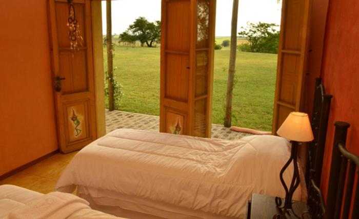 Habitación doble con camas blancas y puertas abiertas al jardín en Alquimia Posada