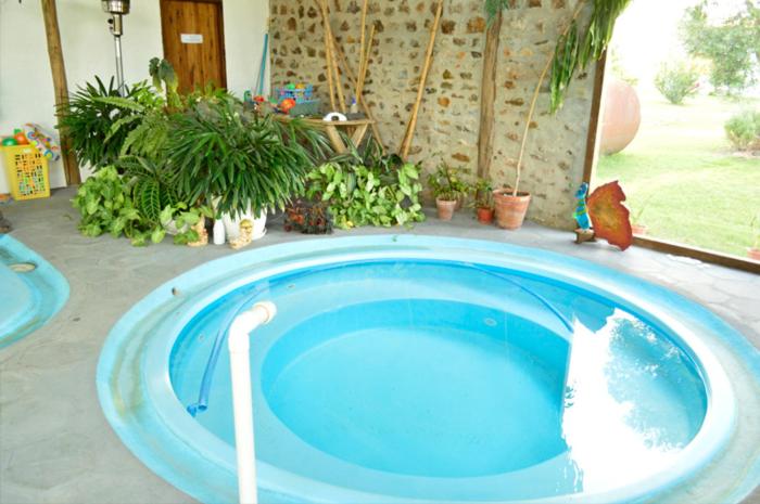 Jacuzzi circular cubierto con agua turquesa y plantas tropicales en Alquimia Posada