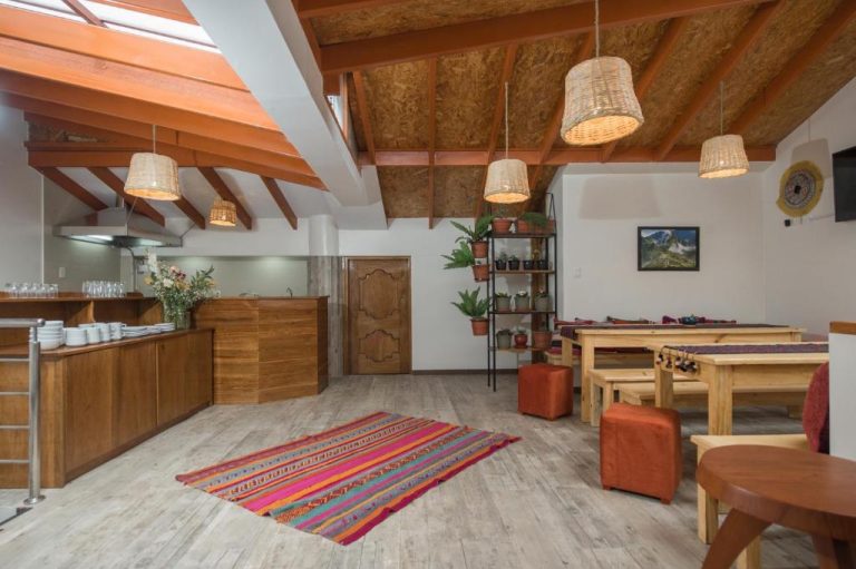 Comedor y cocina rústica con vigas de madera y alfombra andina en Casa Matara Boutique