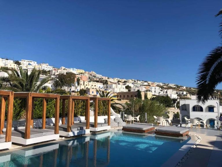 Piscina exterior con tumbonas y vistas al pueblo blanco de Santorini en Callia Retreat Suites Adults Only