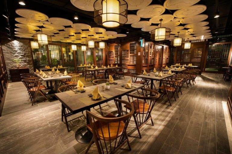 Elegante restaurante interior del Jazz Hotel Penang con mesas de madera, sillas y decoración de lámparas orientales