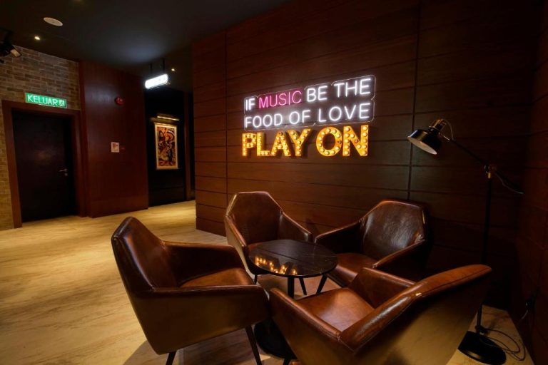 Sala lounge con sillones de cuero y decoración musical neón en Jazz Hotel Penang