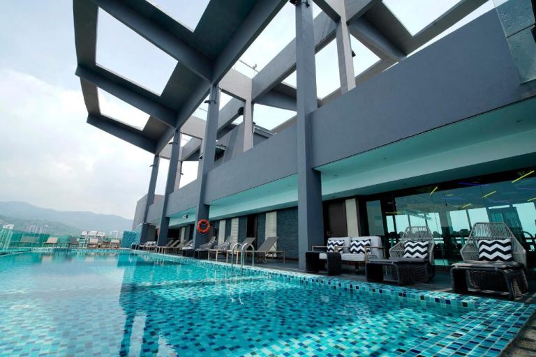 Piscina infinity en la azotea del Jazz Hotel Penang con tumbonas y vistas panorámicas a la ciudad