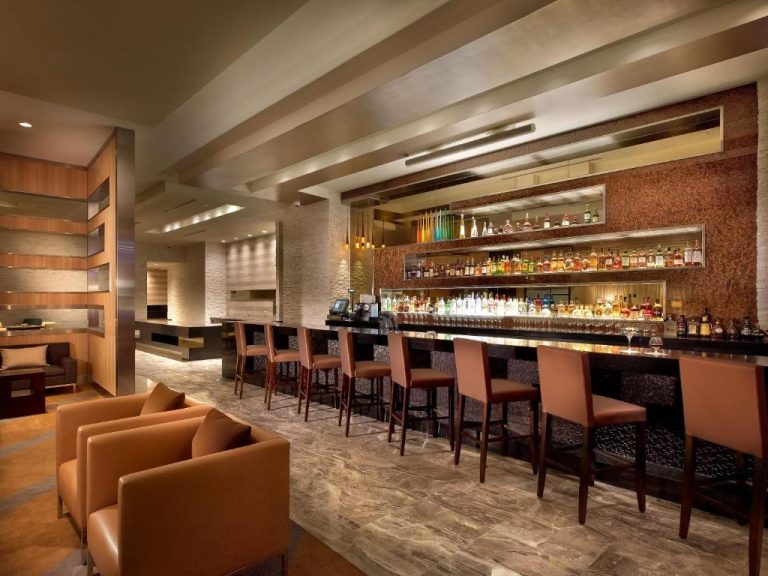 Bar lounge elegante con taburetes y amplia selección de bebidas en el EB Hotel Miami Airport
