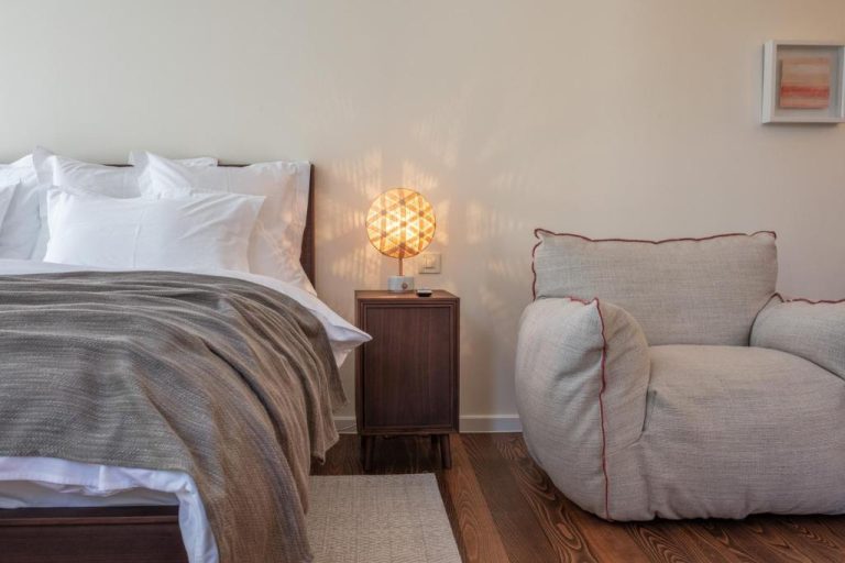 Habitación doble con cama king, sillón gris y lámpara decorativa en Boutique Hotel Boškinac