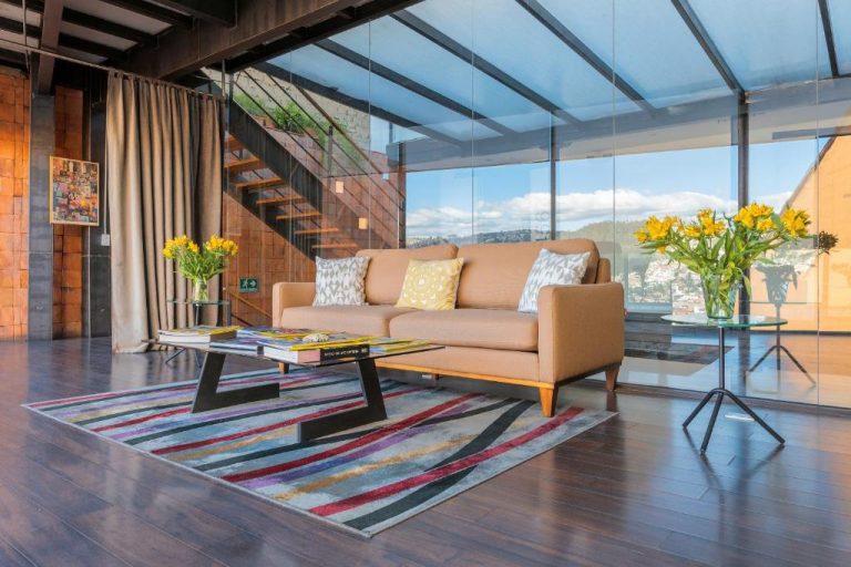 Sala de estar moderna con sofá, terraza acristalada y vistas panorámicas en Hotel Casa Gardenia