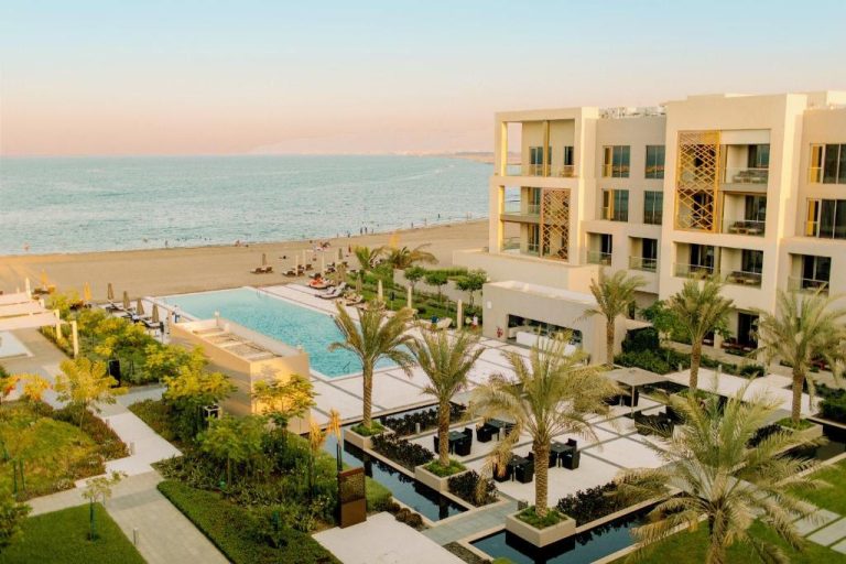 Piscina infinita con vistas al mar y jardines tropicales del Kempinski Hotel Muscat en Omán