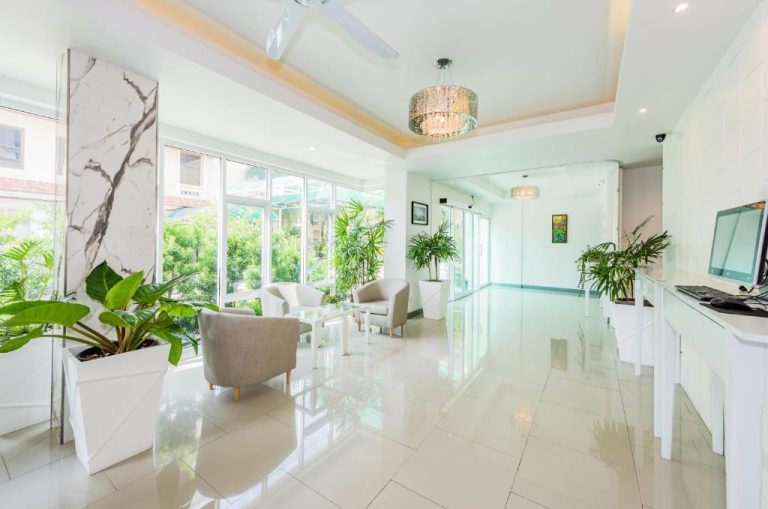 Luminoso lobby con recepción blanca y plantas tropicales del Park 38 Hotel