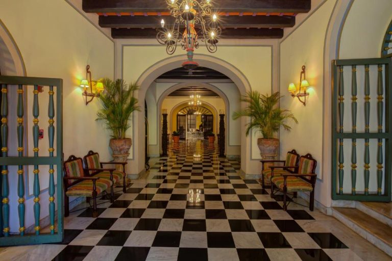 Lobby colonial con suelo de ajedrez y arcos del Hotel El Convento, decorado con lámparas y plantas tropicales