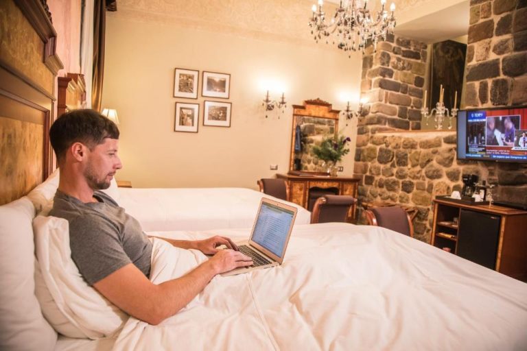 Huésped trabajando con laptop en lujosa habitación del Aranwa Cusco Boutique Hotel con decoración colonial