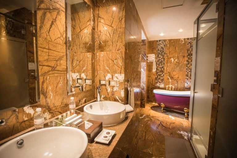 Baño de lujo con mármol dorado y bañera rosa clásica en Aranwa Cusco Boutique Hotel