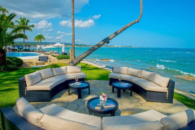 Zona lounge exterior con sofás curvos y vistas al mar turquesa en Velero Beach Resort