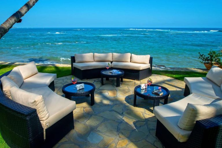 Terraza exterior con sofás de ratán y vistas al mar turquesa en Velero Beach Resort