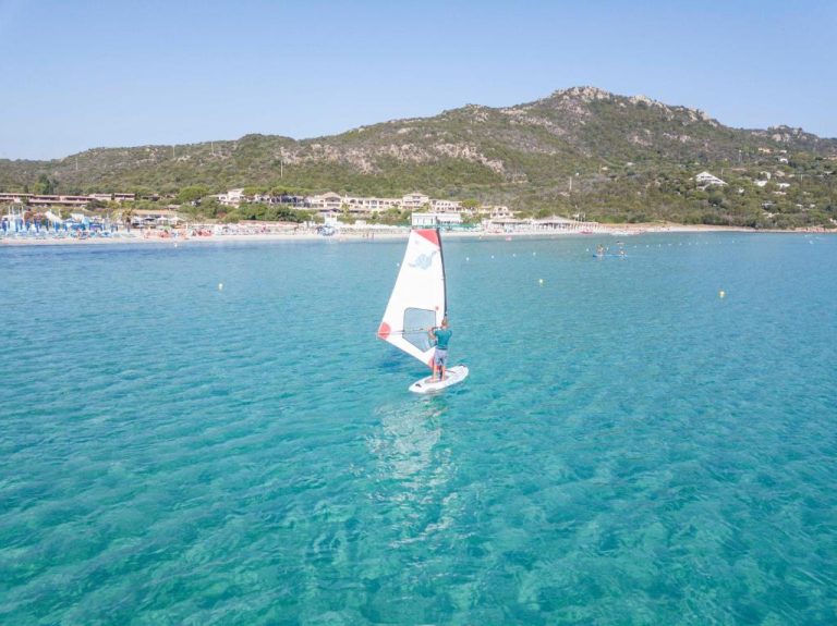 Persona practicando windsurf en las aguas turquesas del Abi d'Oru Sardinian Beach Resort & Spa en Cerdeña