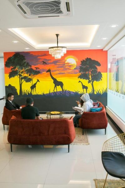 Lobby del Savana Hotel con mural de safari africano y cómodos sofás rojos para huéspedes