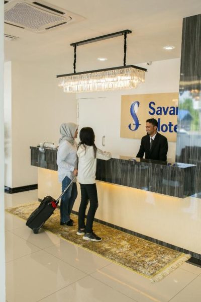 Recepción del Savana Hotel con huéspedes realizando el check-in en el mostrador de bienvenida