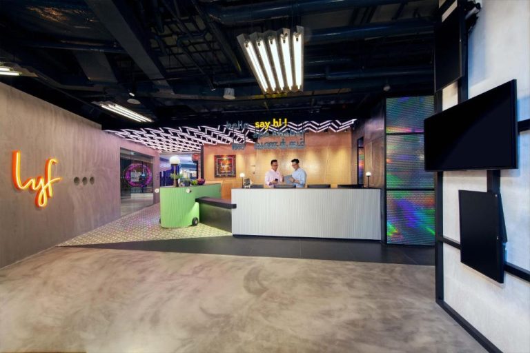 Recepción moderna con decoración neón y diseño urbano del hotel lyf Funan Singapore