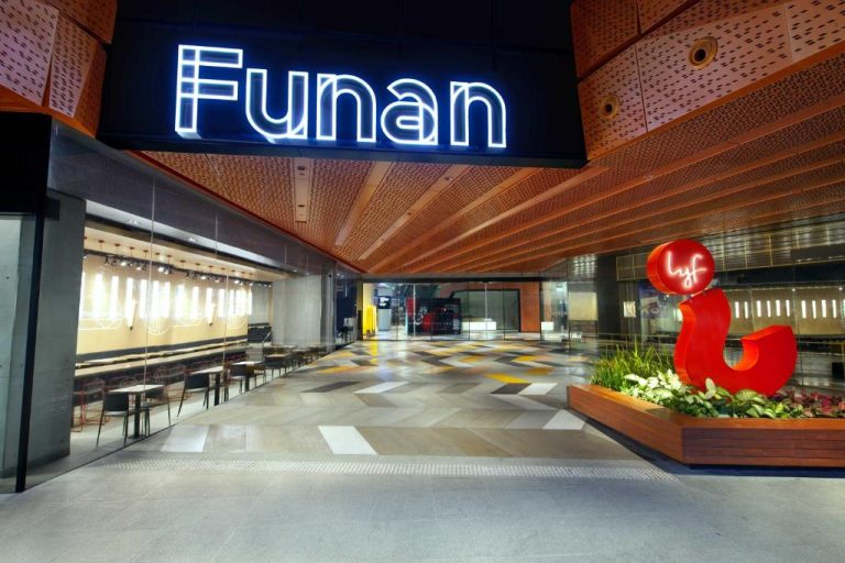 Entrada principal del hotel lyf Funan Singapore con iluminación nocturna y zona de restaurantes
