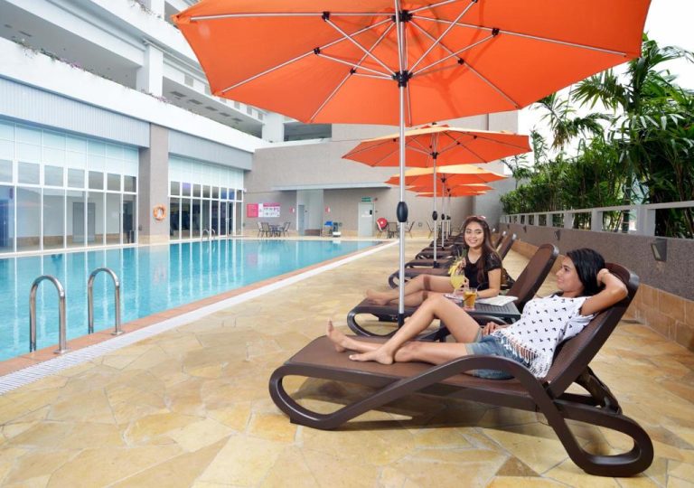 Turistas relajándose en tumbonas junto a la piscina exterior del Lexis Suites Penang