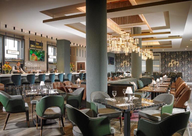 Elegante restaurante The Brasserie del Fairways Hotel Dundalk con mesas de mármol y lámparas de cristal