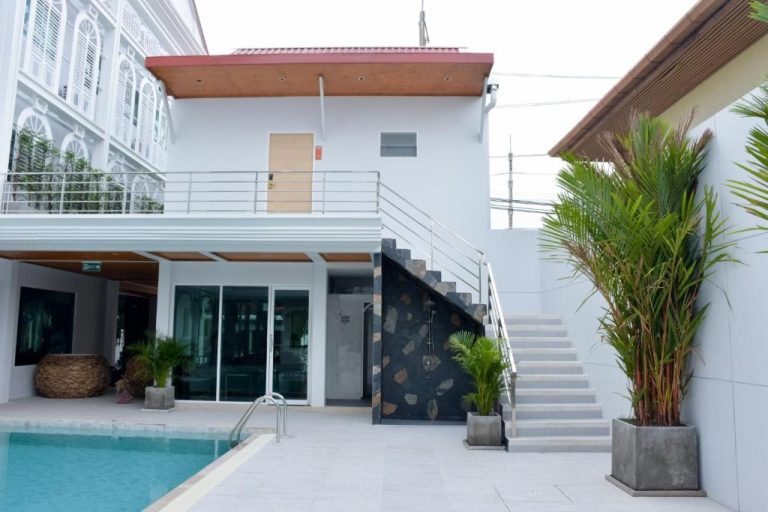 Piscina exterior con terraza y escaleras del Peranakan House, rodeada de palmeras tropicales