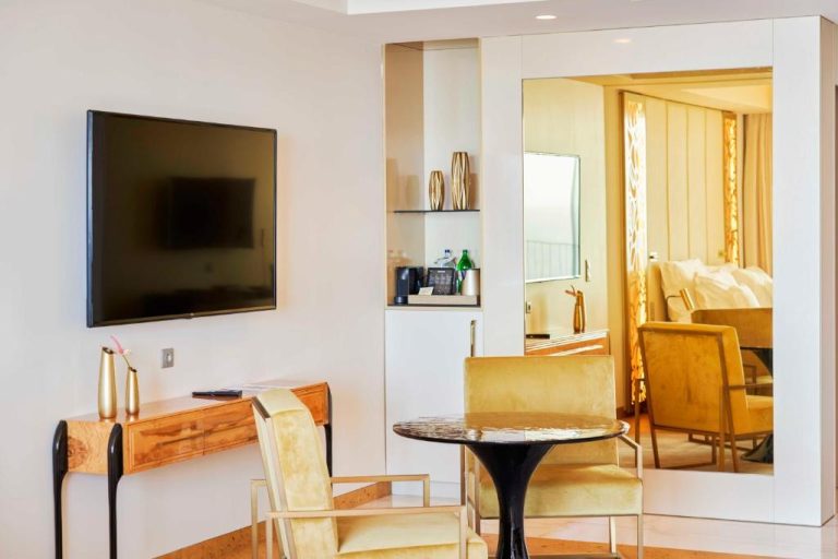 Salón de suite en Savoy Palace con sillas doradas, mesa de mármol, TV y espejo de cuerpo entero