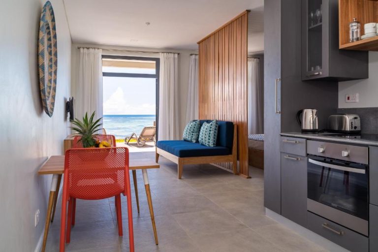 Estudio con cocina equipada y vistas al mar en La Desirade, con sofá azul y terraza frente al océano