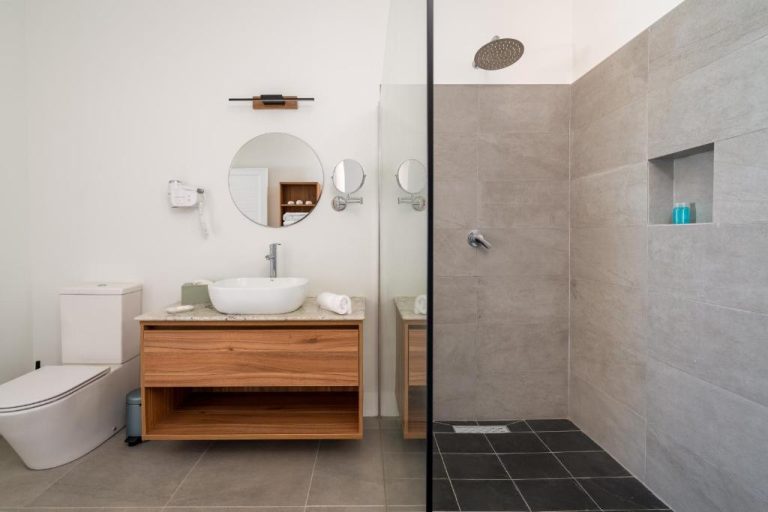 Baño moderno con ducha de lluvia y lavabo sobre encimera de madera en Hotel La Desirade