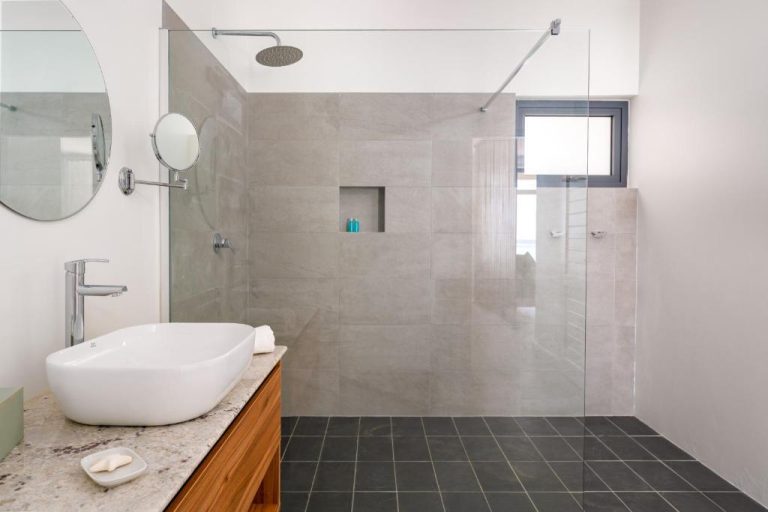 Baño moderno con ducha de lluvia y lavabo sobre encimera de mármol en La Desirade