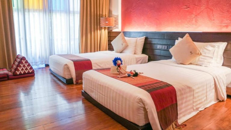 Habitación doble con decoración tradicional tailandesa y cabecero rojo en De Lanna Hotel