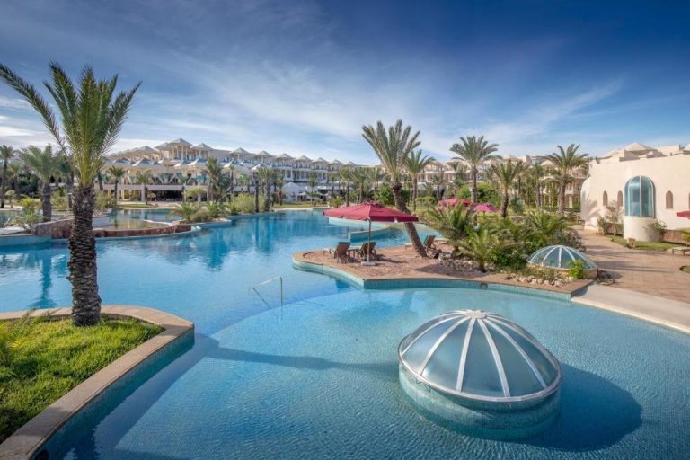 Amplia piscina exterior con palmeras y zona de descanso del Hasdrubal Prestige Thalassa & Spa Djerba