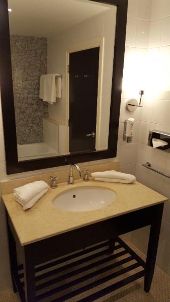 Baño moderno con lavabo, espejo y toallas blancas del Shamrock Lodge Hotel