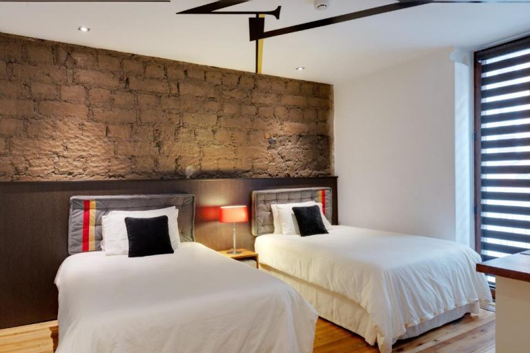 Habitación doble con dos camas y pared de piedra rústica en el Hotel Casa Gardenia