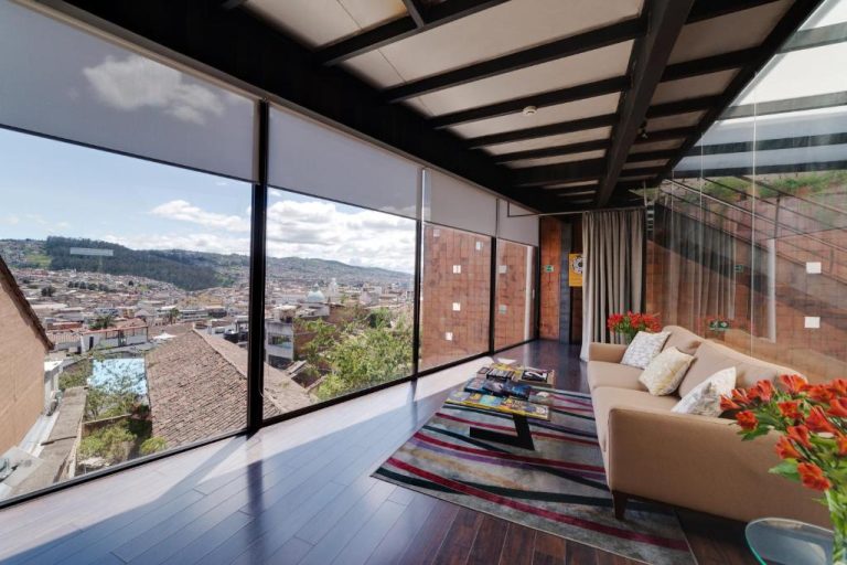 Sala de estar con vista panorámica a la ciudad en Hotel Casa Gardenia con sofá y grandes ventanales