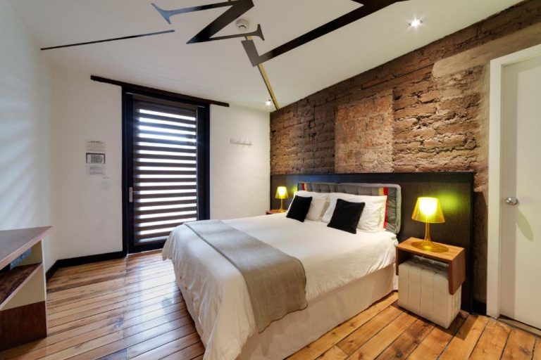 Habitación doble con pared de piedra vista y suelo de madera en Hotel Casa Gardenia