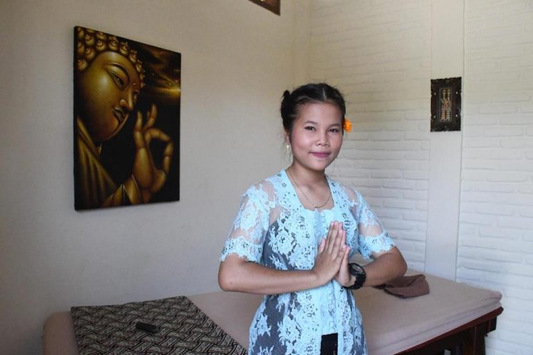 Terapeuta de spa del Bruga Boutique Hotel dando la bienvenida con gesto namaste en sala de masajes
