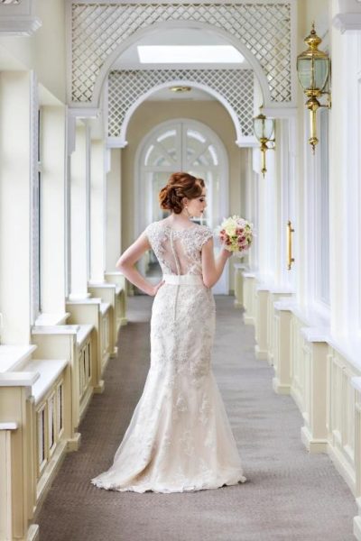 Novia con vestido de encaje y ramo de flores en el elegante pasillo del Connemara Coast Hotel