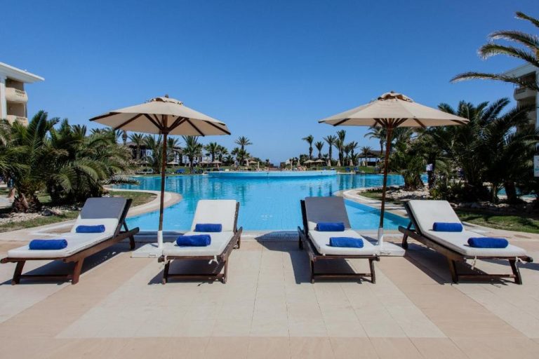 Piscina exterior con tumbonas y sombrillas del Royal Thalassa Monastir rodeada de palmeras