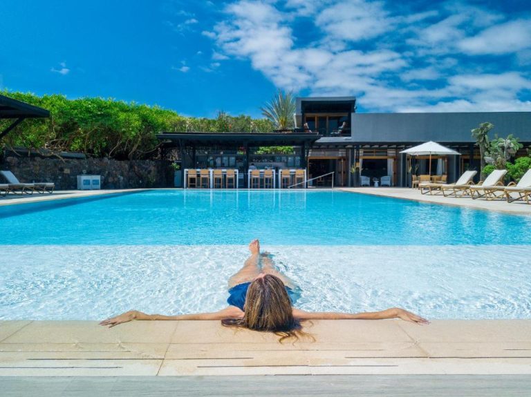 Mujer relajándose en la piscina exterior del Finch Bay Galapagos Hotel con bar y jardín tropical