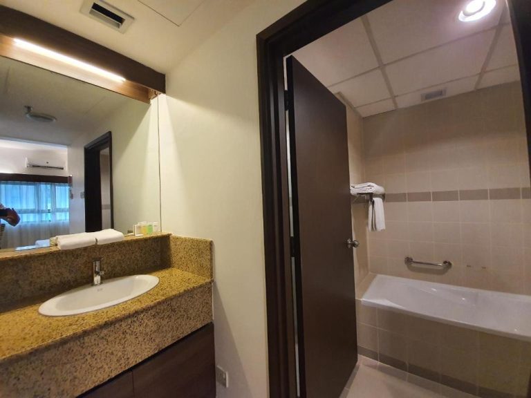 Baño completo con bañera y lavabo de mármol en Crown Regency Serviced Suites