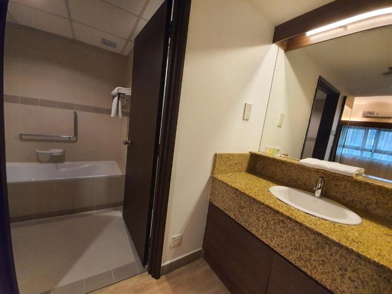 Baño completo con bañera y lavabo de mármol en Crown Regency Serviced Suites
