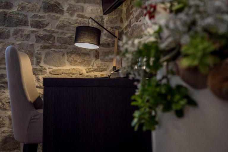 Escritorio con lámpara de diseño y silla elegante junto a pared de piedra en Murum Heritage Hotel