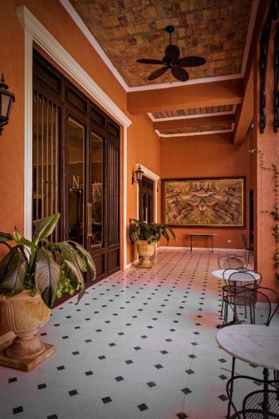 Terraza interior colonial del Nino Hotel Boutique con suelo de mármol, plantas tropicales y cuadro artístico