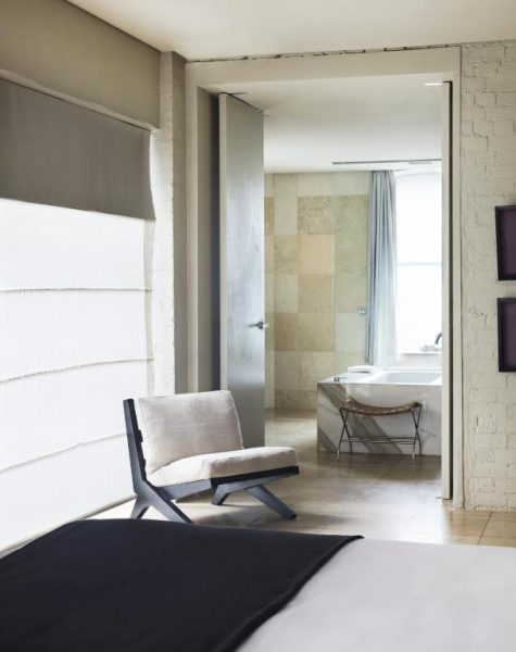 Suite de lujo con silla de diseño y baño con bañera exenta en Establishment Hotel