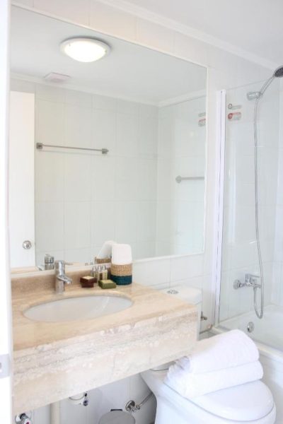 Baño completo con ducha, lavabo de mármol y espejo grande en Apart Hotel Providencia