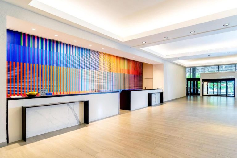 Recepción del Hyatt Regency Miami con mural de arte colorido y mostrador de mármol blanco